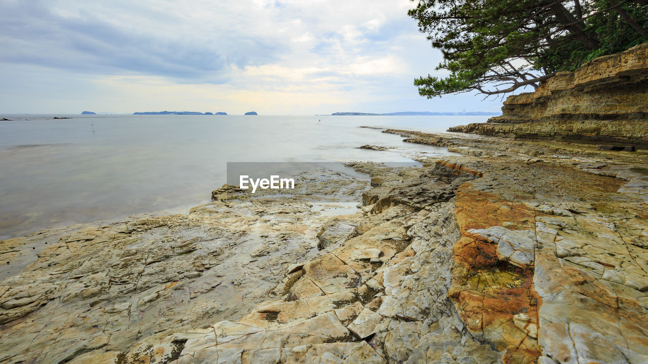 SCENIC VIEW OF ROCKS ON BEACH AGAINST SKY