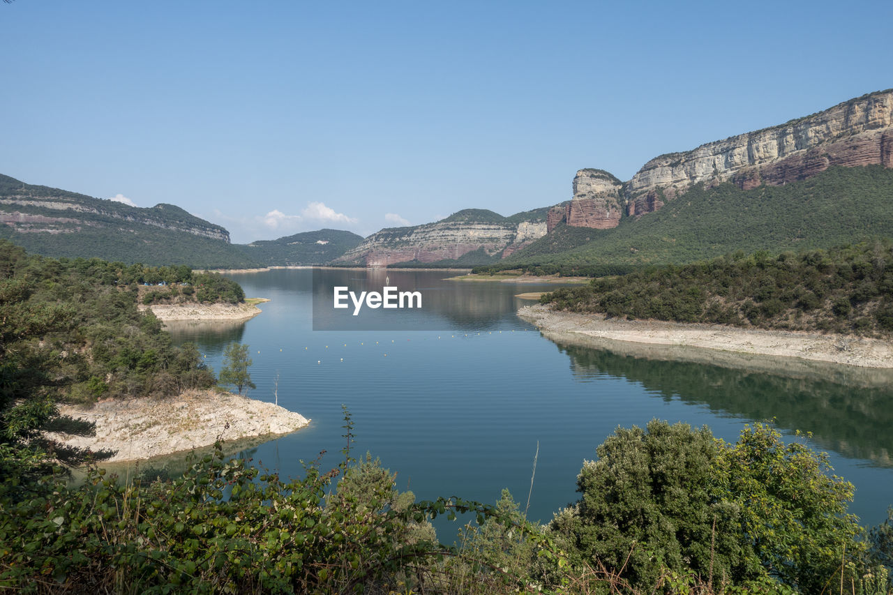 Scenic view of lake and mountains against clear blue sky