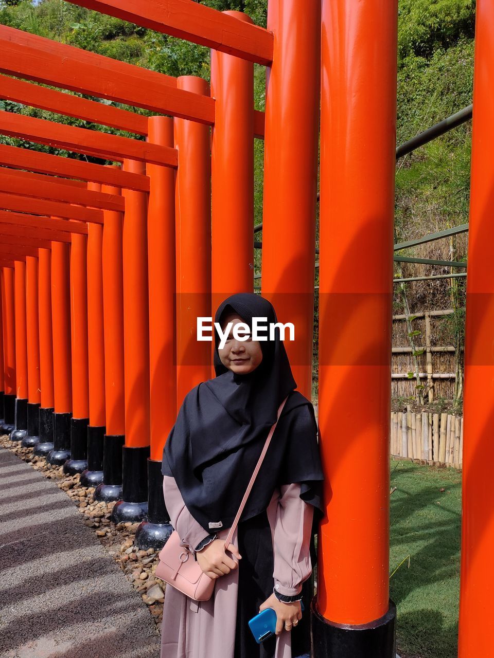 Portrait of teenage girl wearing hijab standing against orange columns