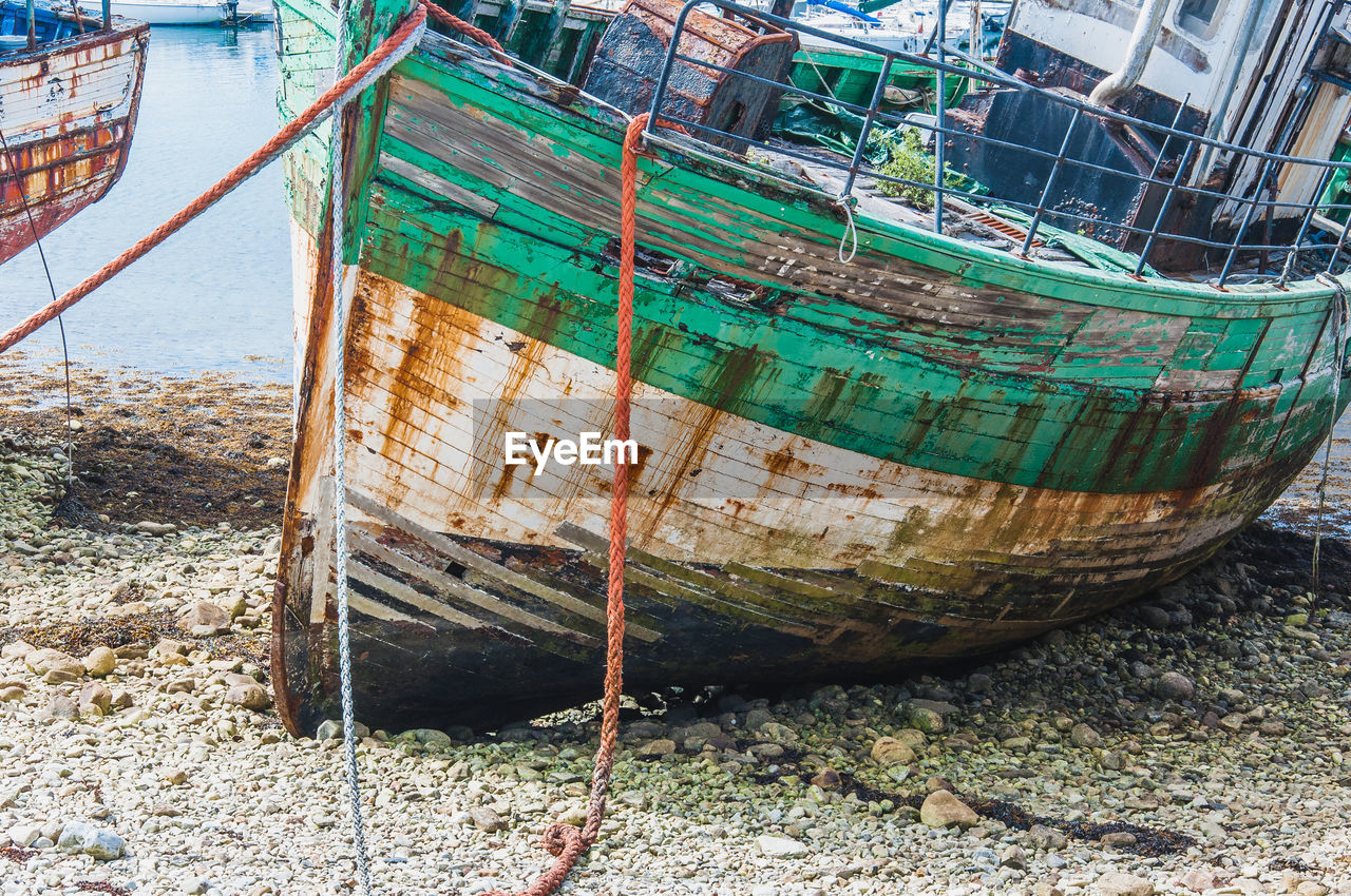 ABANDONED BOAT MOORED ON SHORE