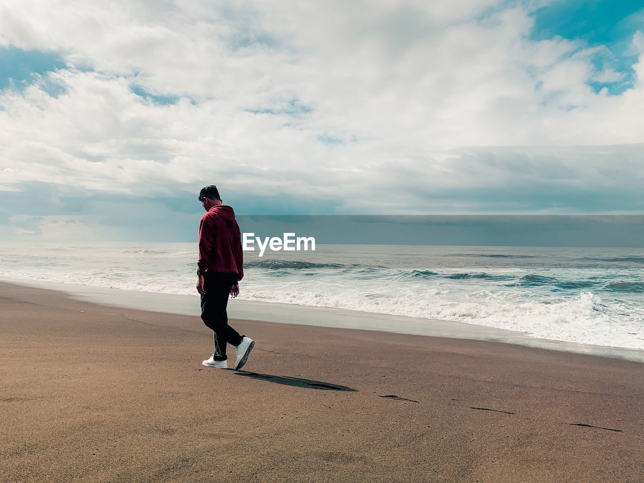 Man walking on the beach while looking down