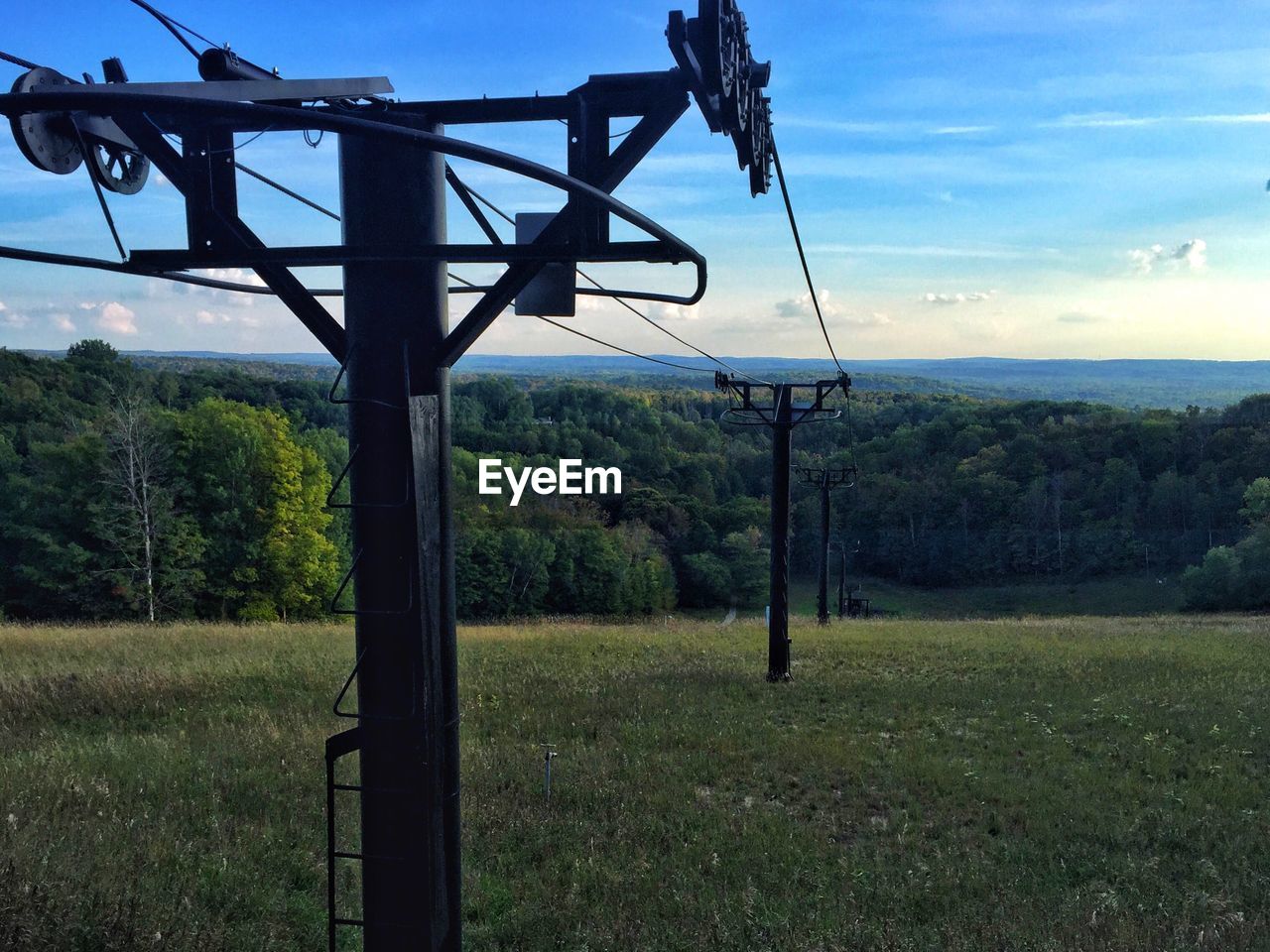 LOW ANGLE VIEW OF OVERHEAD CABLE CAR ON FIELD