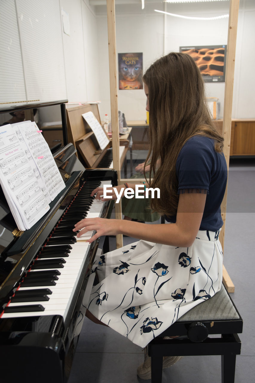 Teenage girl playing the piano in the classroom, music hobby