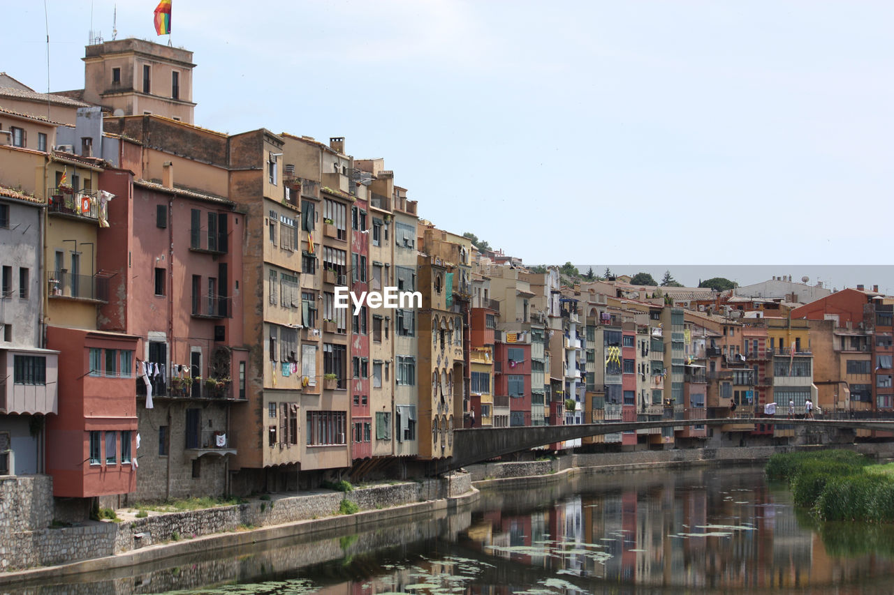 Buildings by river in town against sky