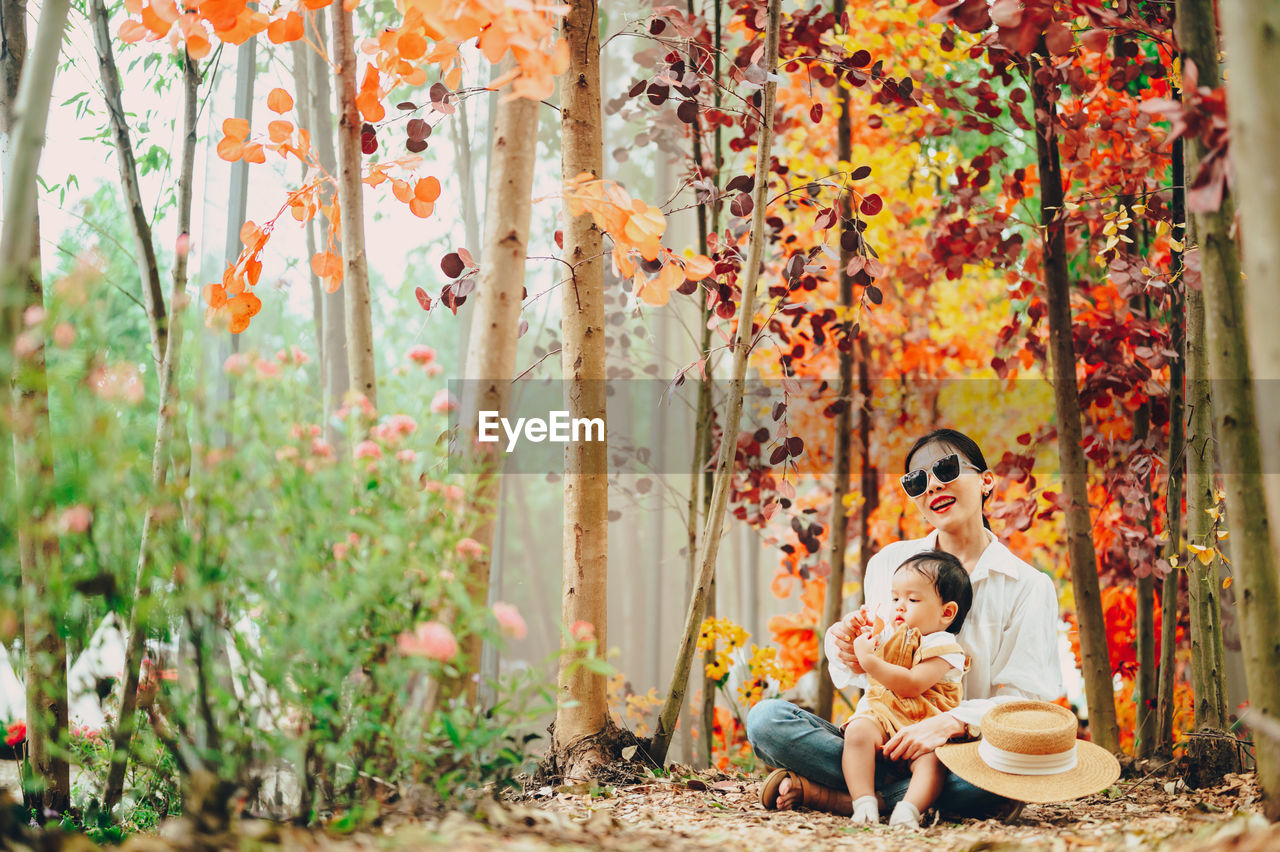 GROUP OF PEOPLE SITTING IN AUTUMN LEAVES