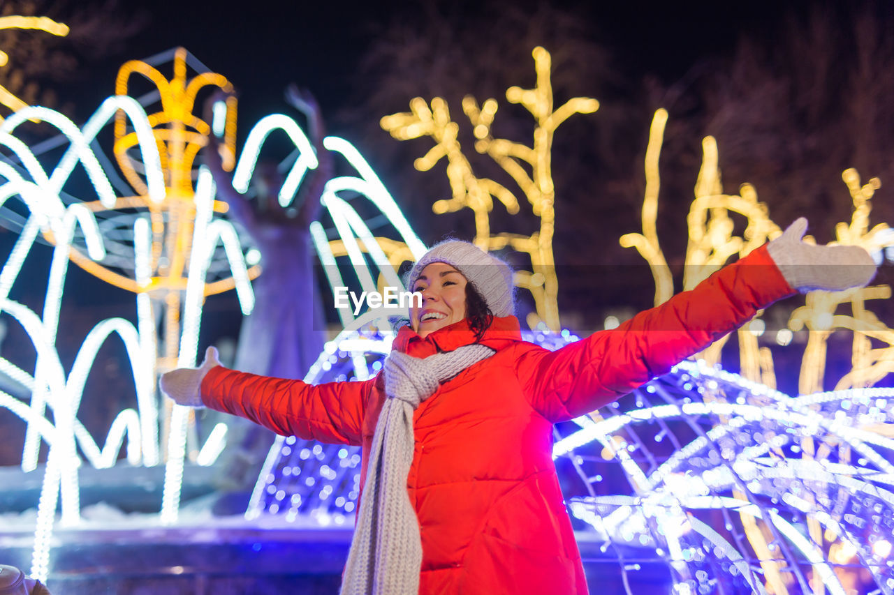 rear view of woman with arms raised standing in city