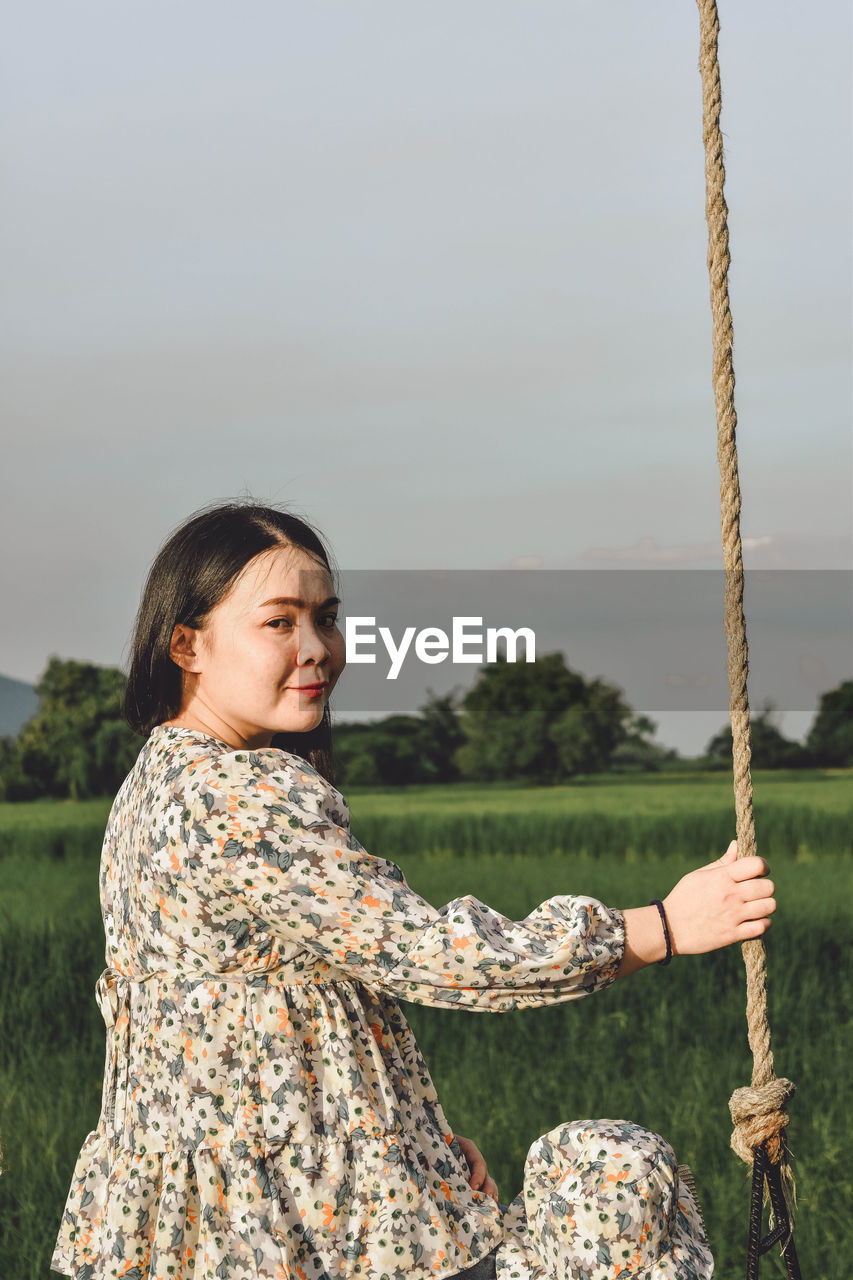 Portrait of woman standing by plants against sky