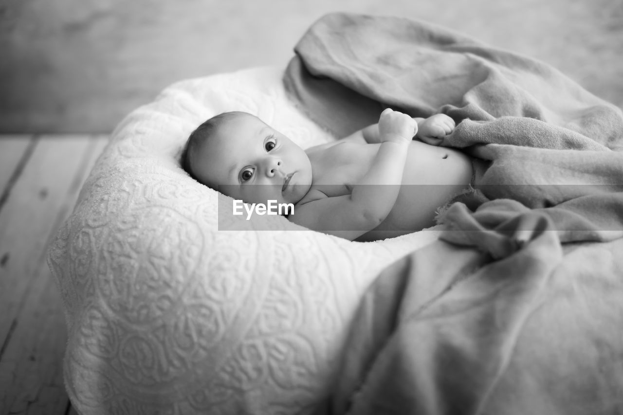 BABY GIRL LYING ON BED AT HOME