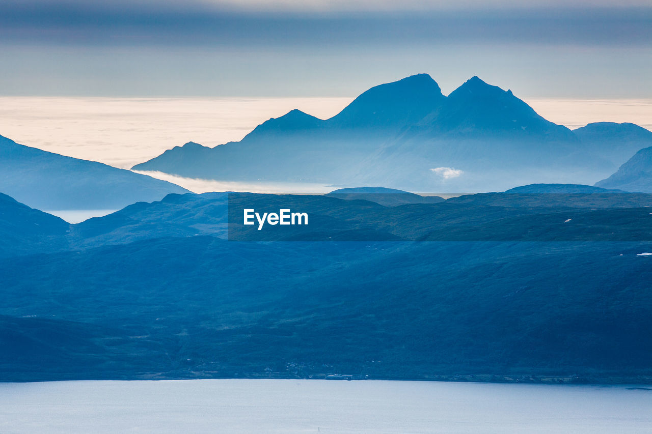 Scenic view of lake by mountains against sky at dusk