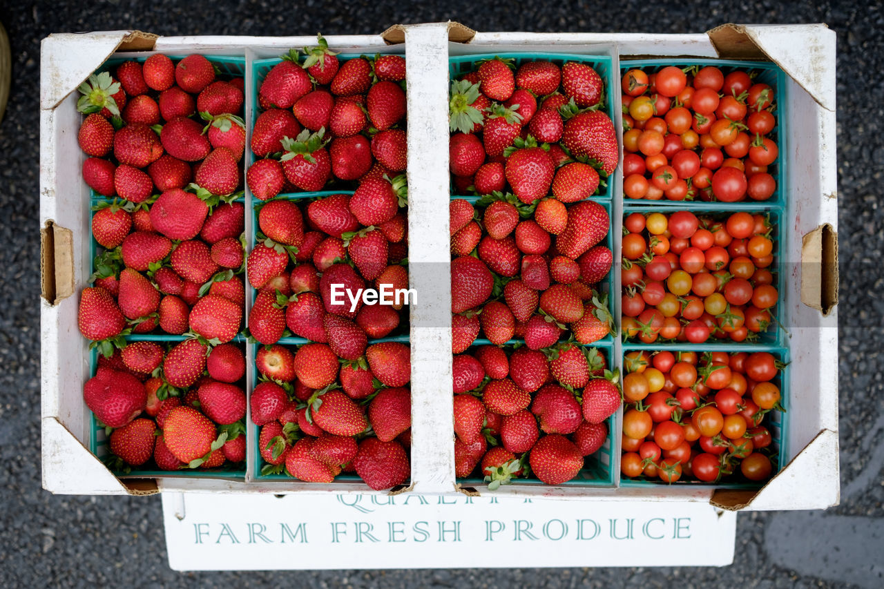 Directly above shot of strawberries and tomatoes in crate for sale at market