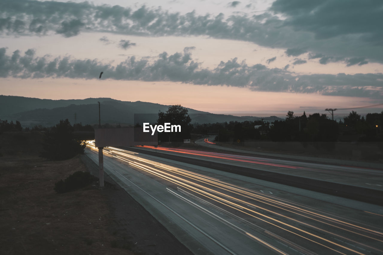 Light trails on road against sky