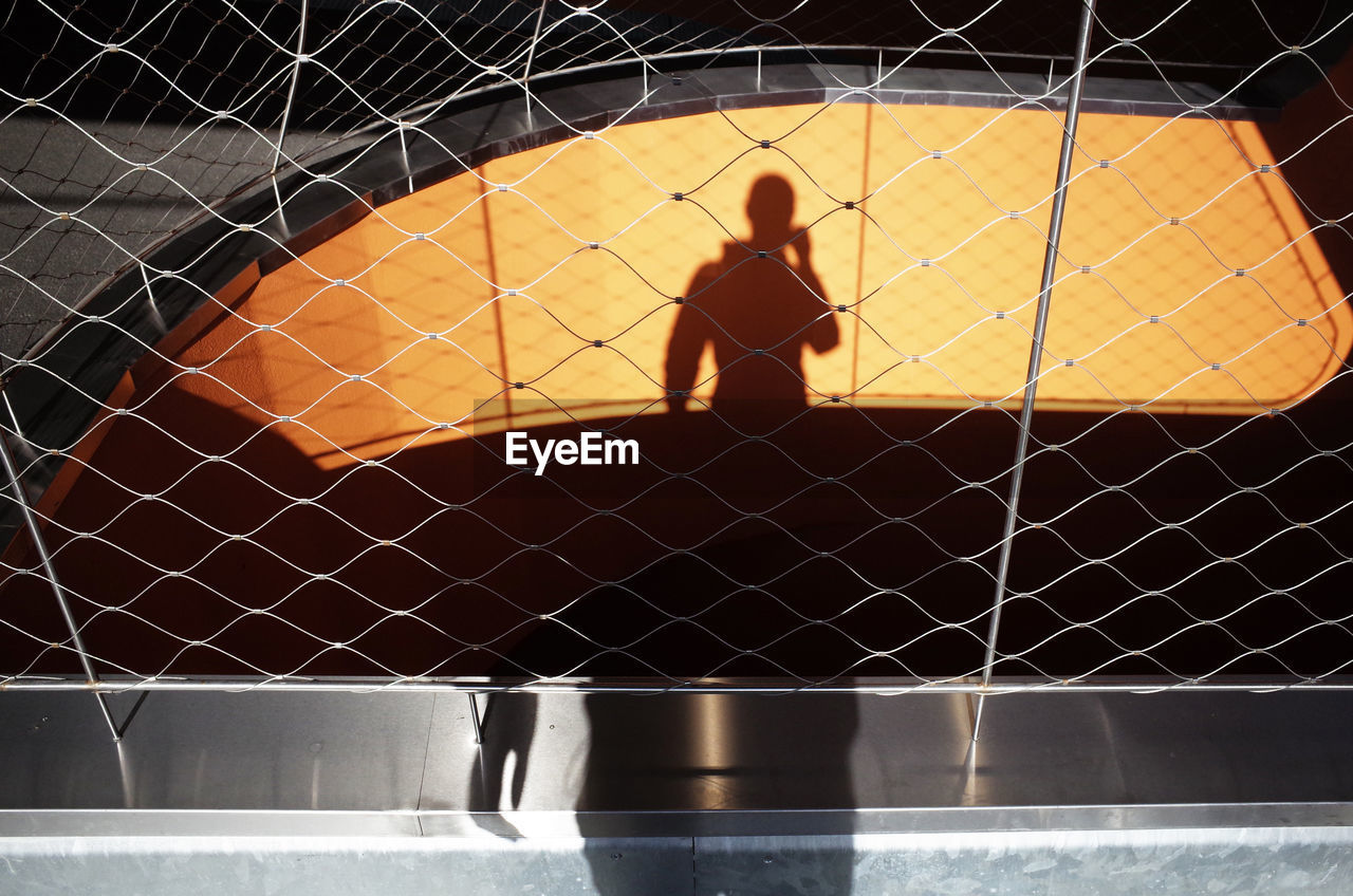 SHADOW OF MAN STANDING ON ILLUMINATED FLOOR