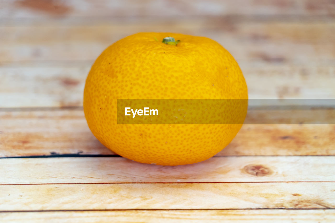 CLOSE-UP OF ORANGE FRUIT ON TABLE