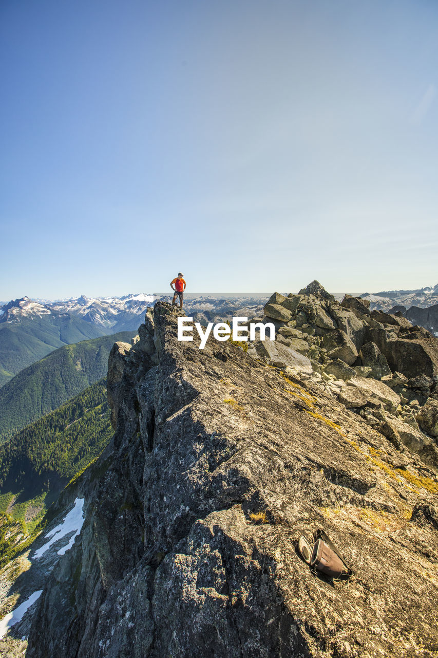 Climber stands on the summit of a rocky mountain peak, b.c. canada