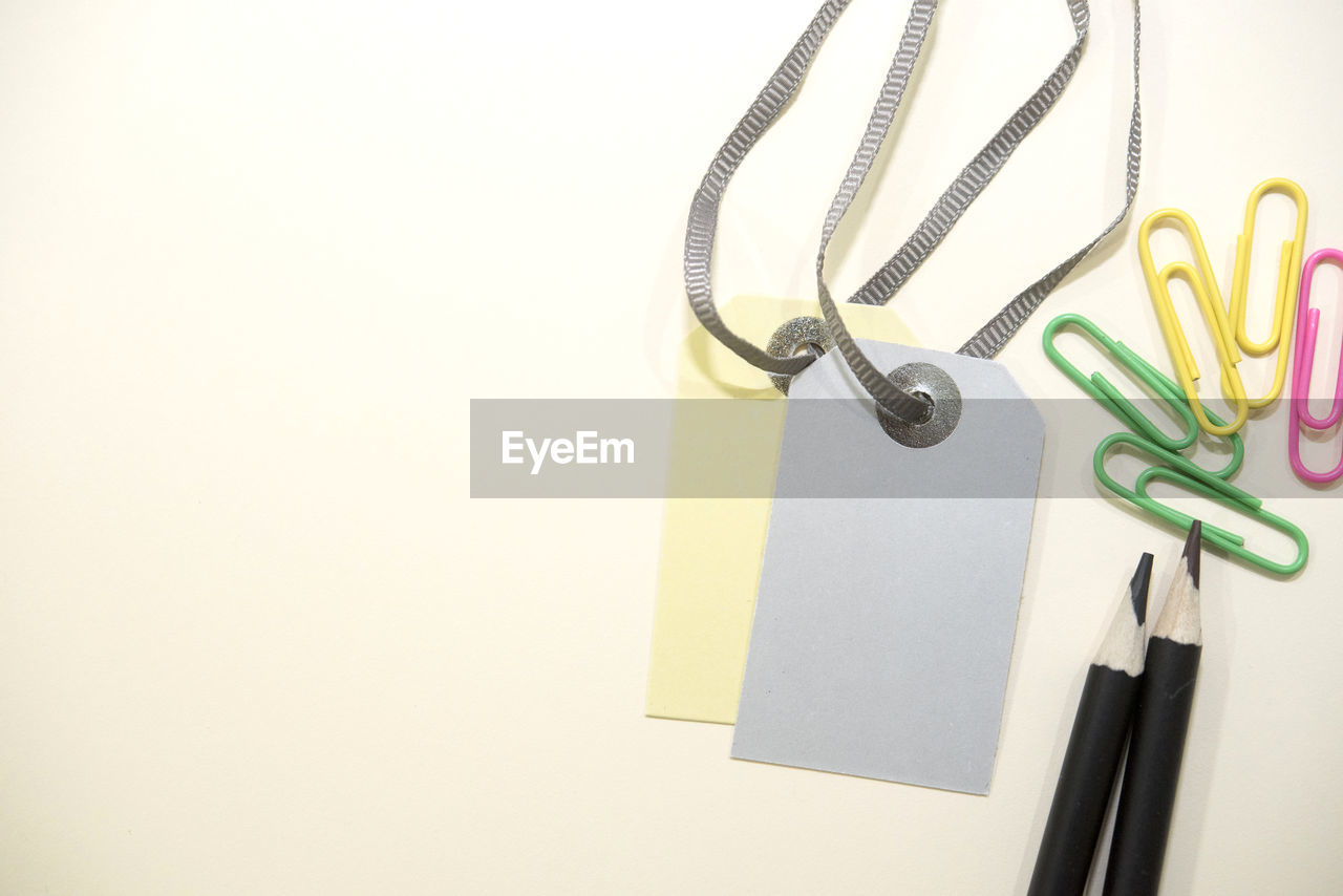 Close-up of labels with paper clips and pencils on white background