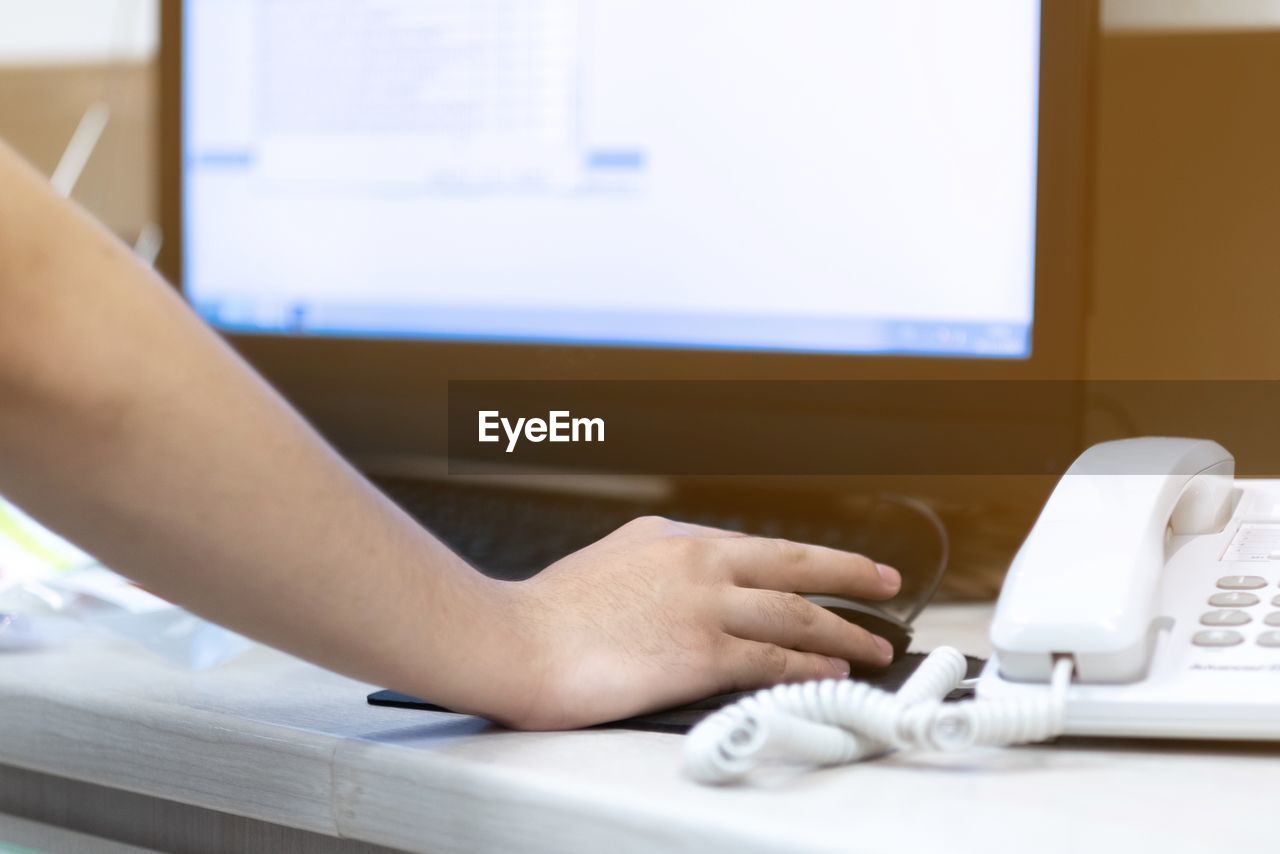 Cropped hand of woman using computer on table