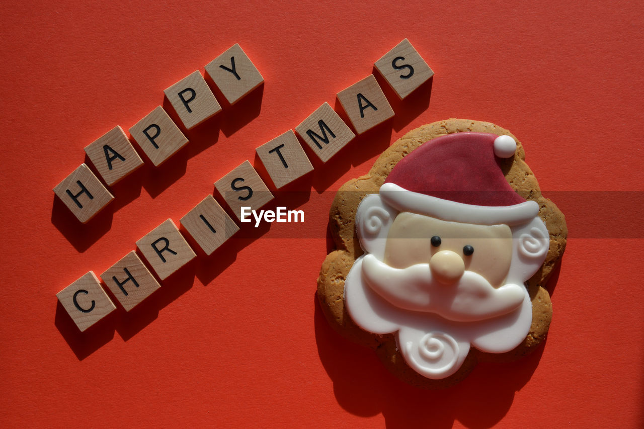 High angle view of happy christmas text and santa gingerbread cookie on red background 