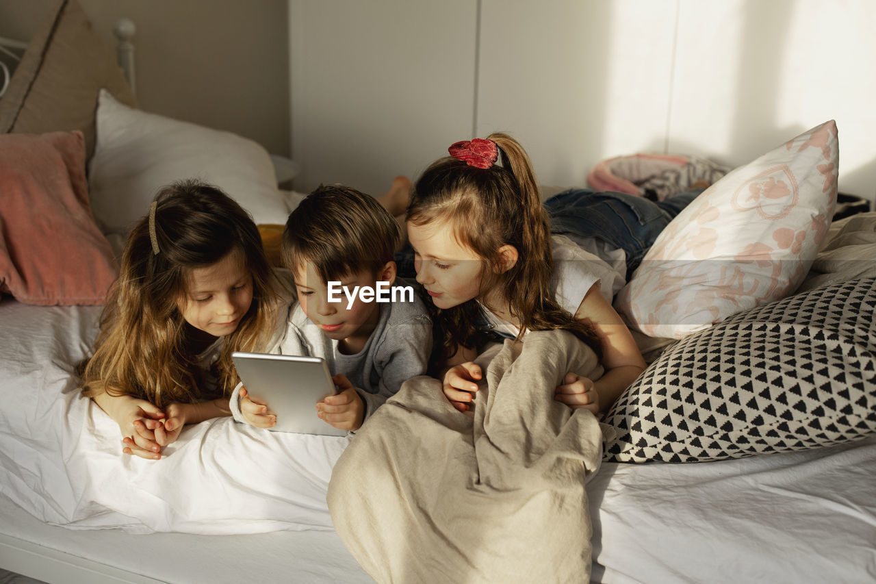 Children on bed using digital tablet