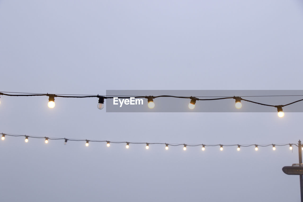 LOW ANGLE VIEW OF ILLUMINATED LIGHT BULB AGAINST SKY