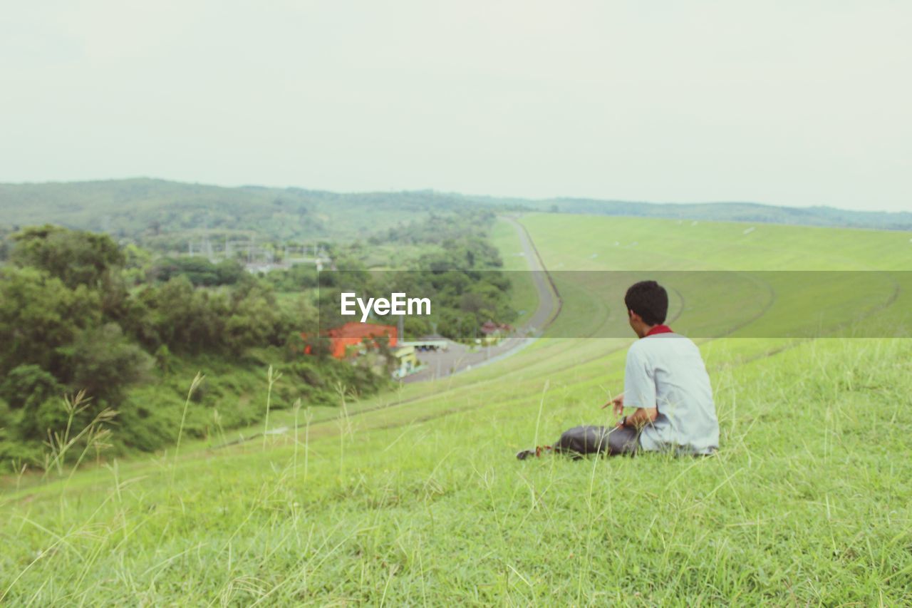 MAN SITTING ON FIELD