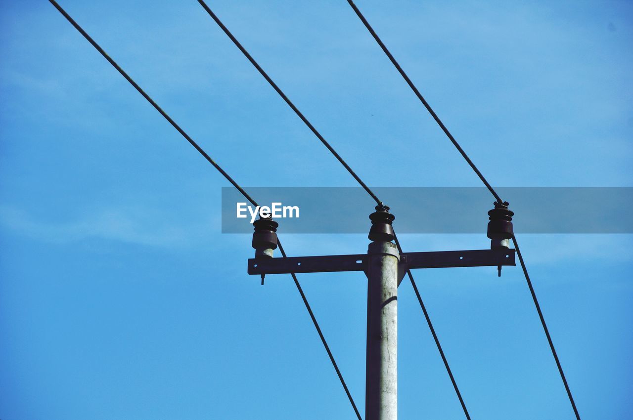 Low angle view of power lines against blue sky