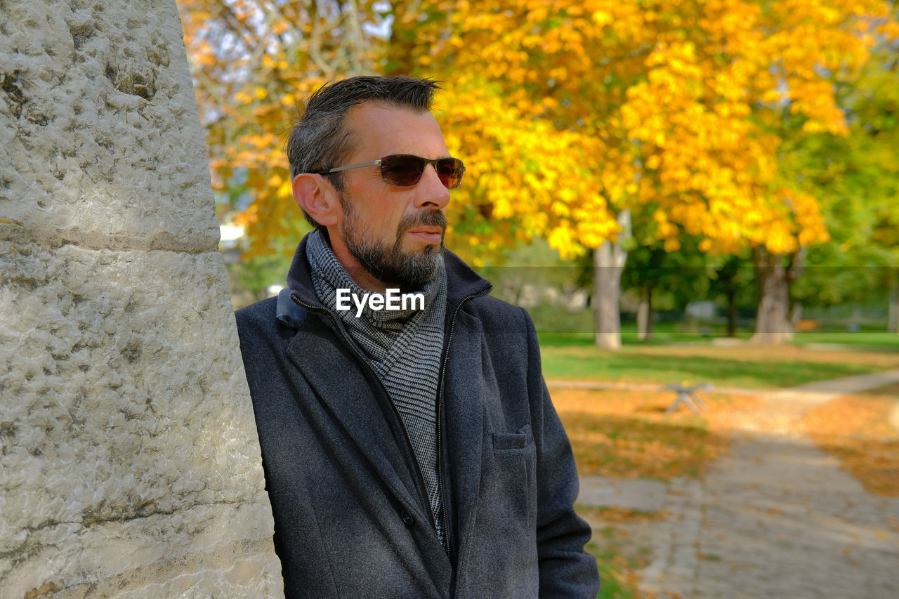 Portrait of young man wearing sunglasses standing against trees