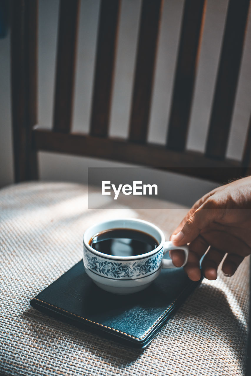 Cropped hand of person holding coffee cup on diary