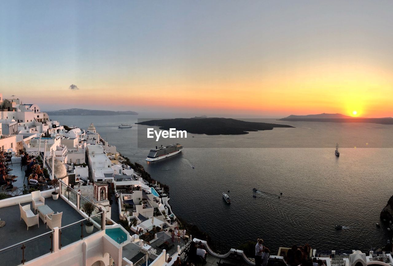 High angle view of city by sea against sky during sunset