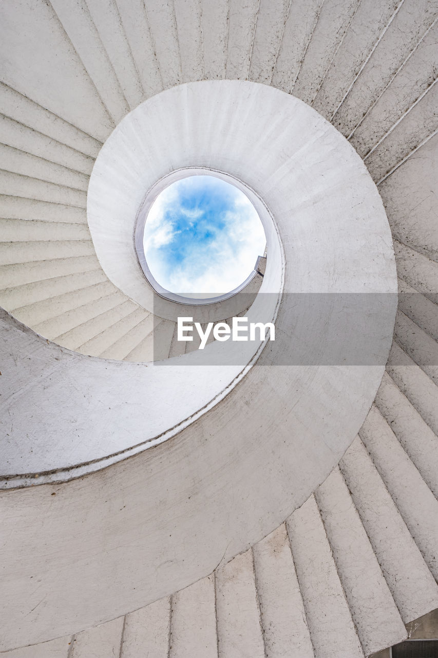 Spiral staircase and cloudy sky