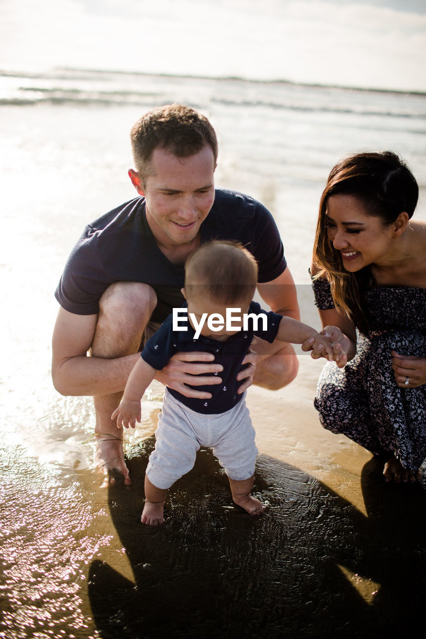 Mid 30's parents playing in ocean with infant son