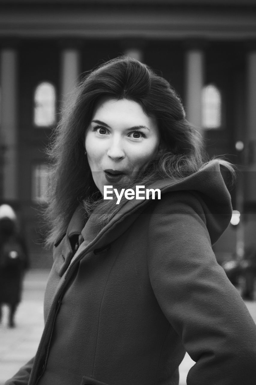 Close up amazed woman in stylish coat on street monochrome portrait picture