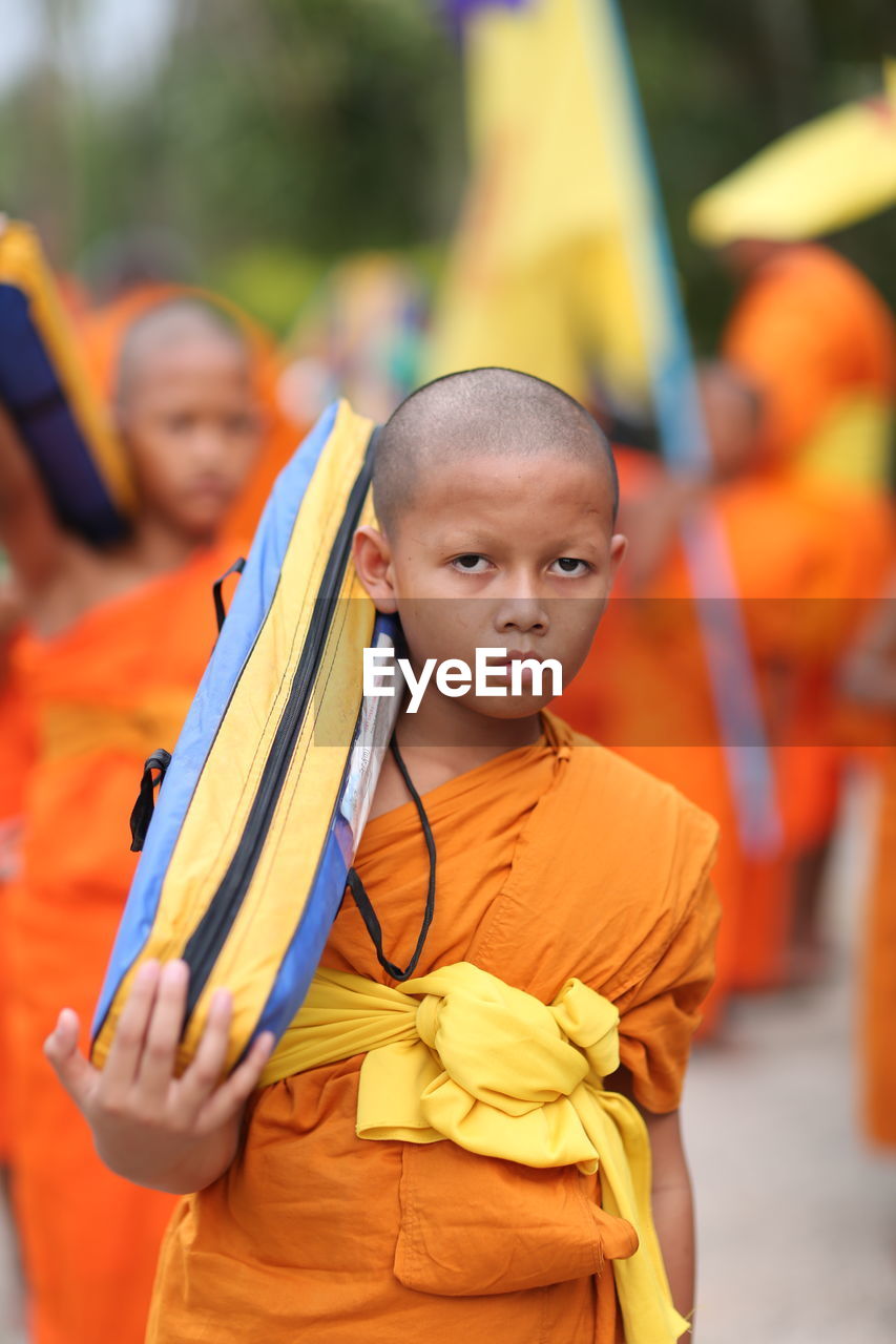 PORTRAIT OF BOY STANDING AGAINST ORANGE SUN