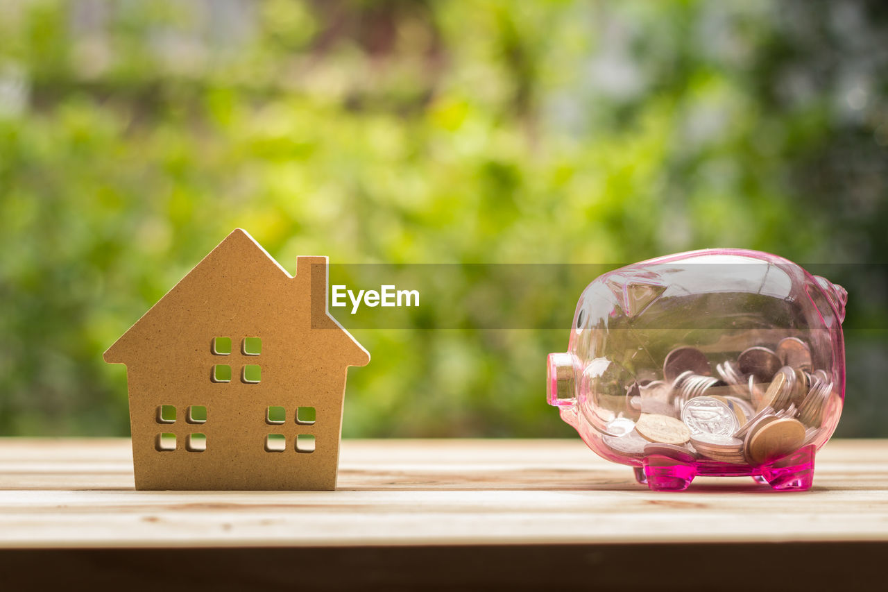 Close-up of house model and piggy bank on table