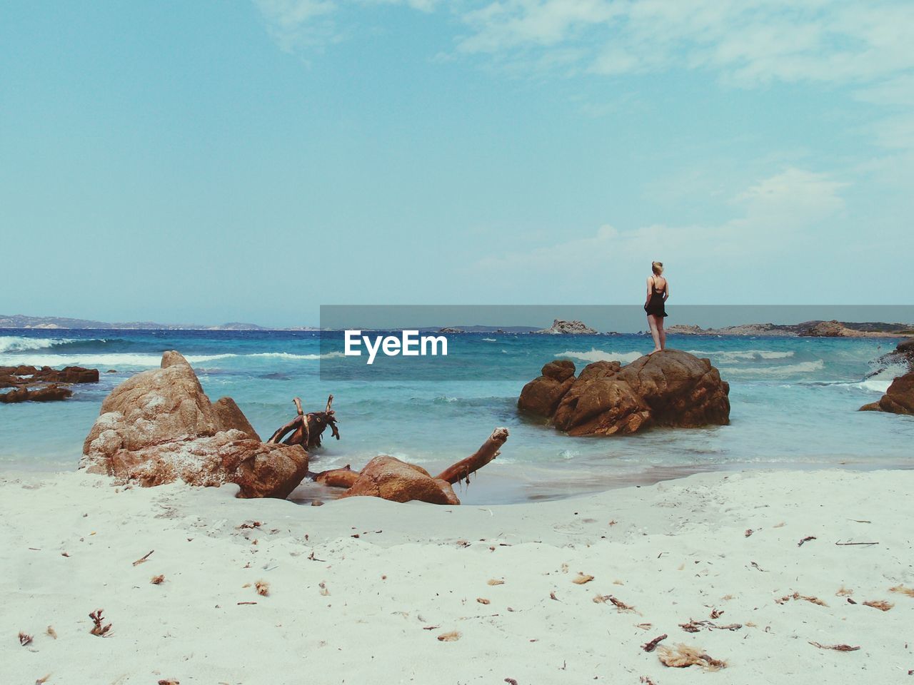 Woman standing on rock at beach against sky