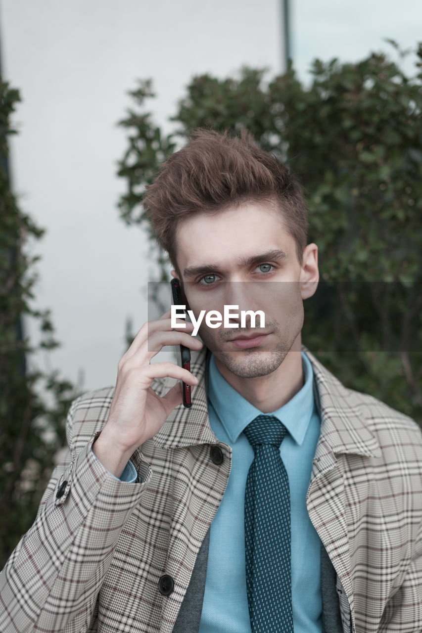 Portrait of businessman talking on mobile phone in city