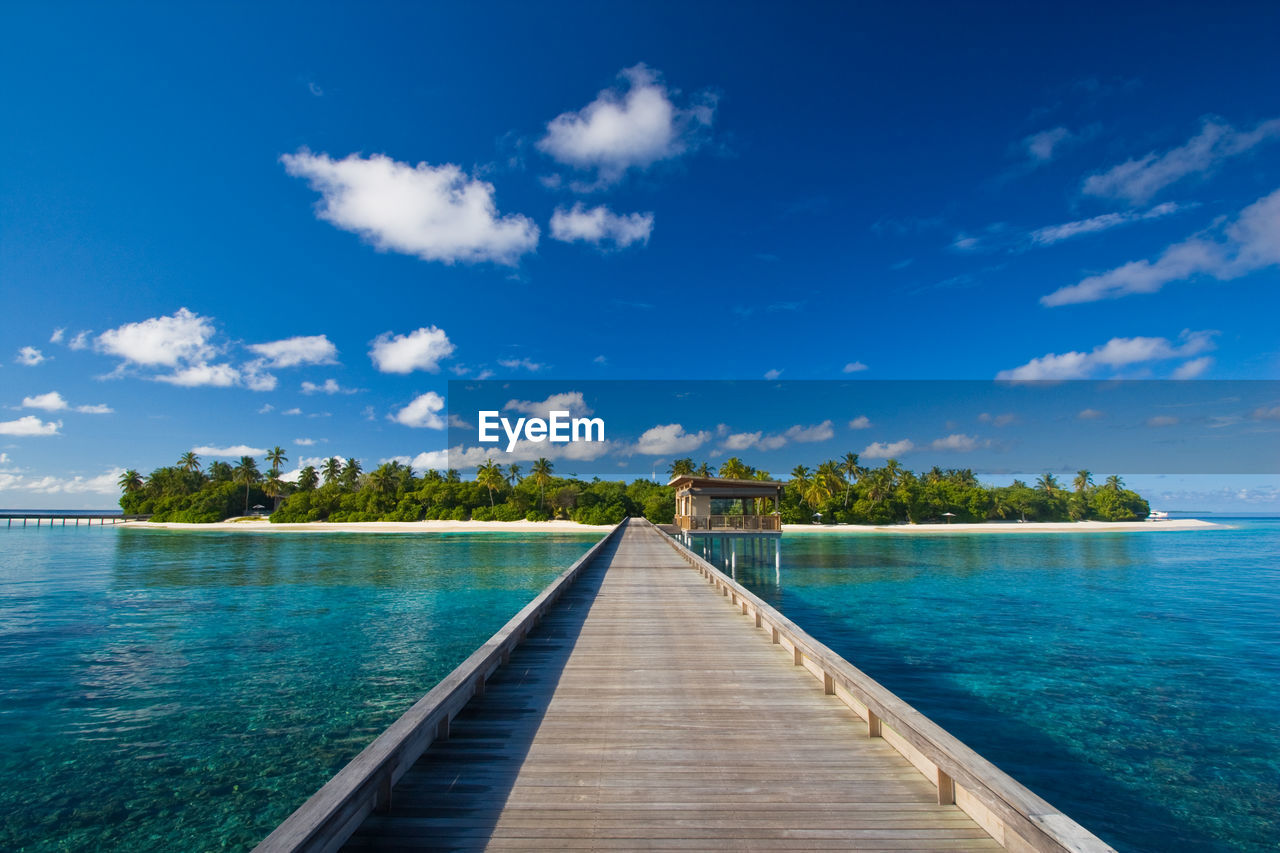 Pier over sea against blue sky