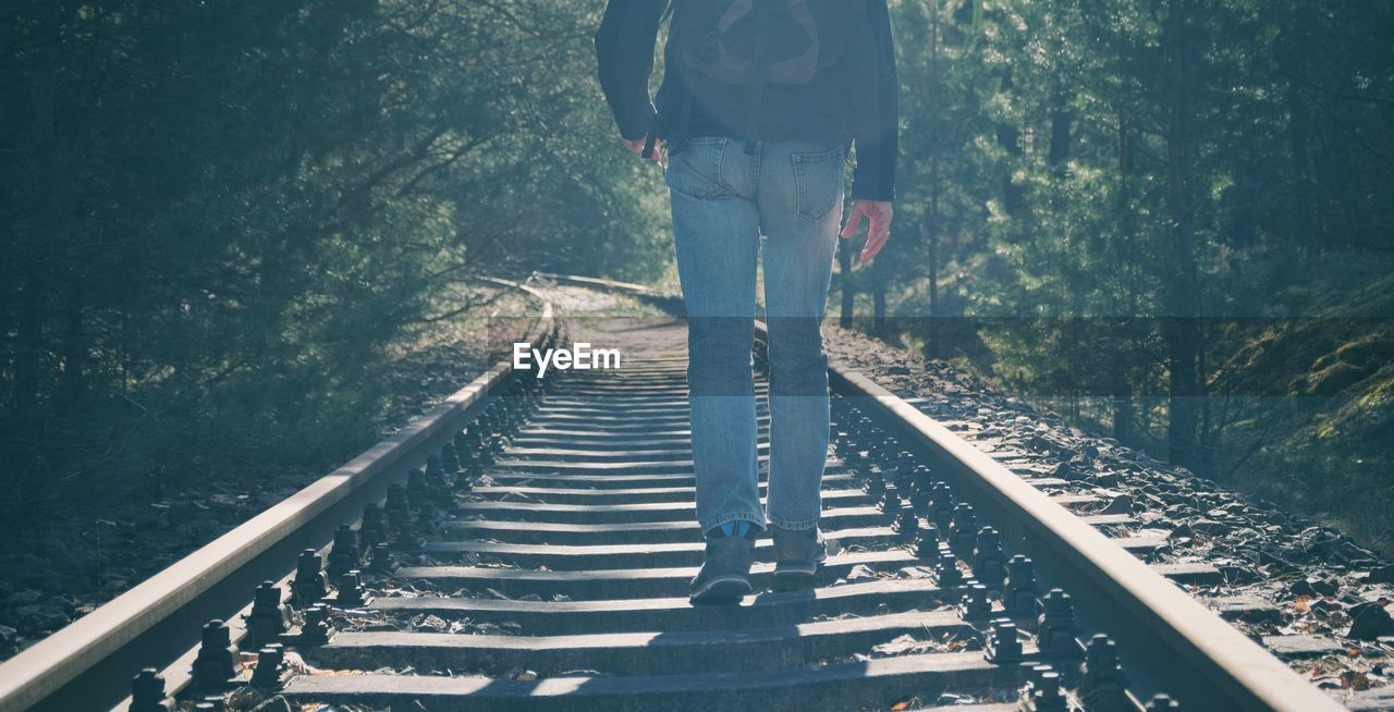 Low section of man walking on railroad tracks