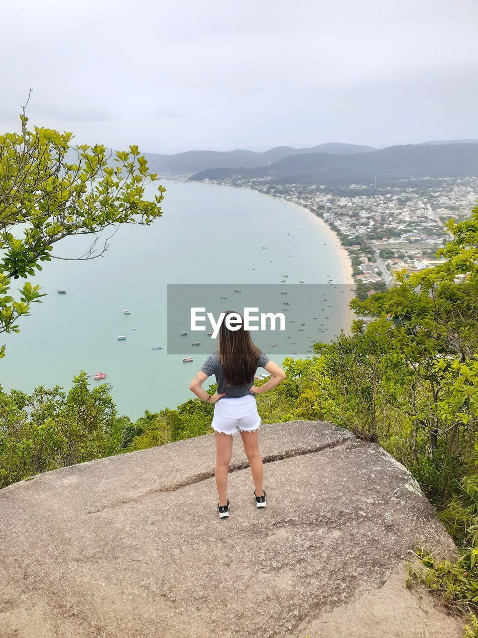 FULL LENGTH REAR VIEW OF WOMAN STANDING BY PLANTS AGAINST SKY