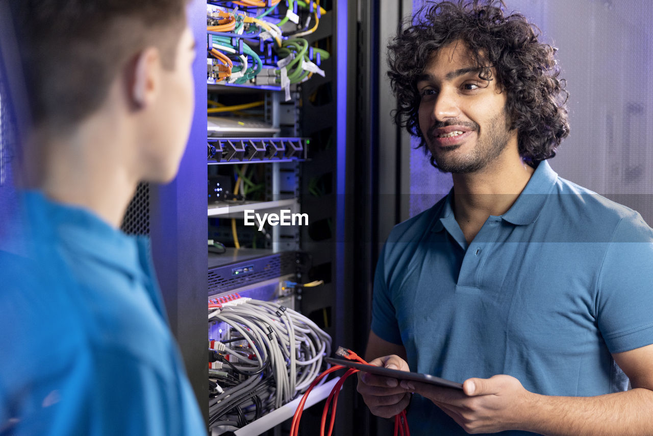 It technician discussing with trainee in server room at industry