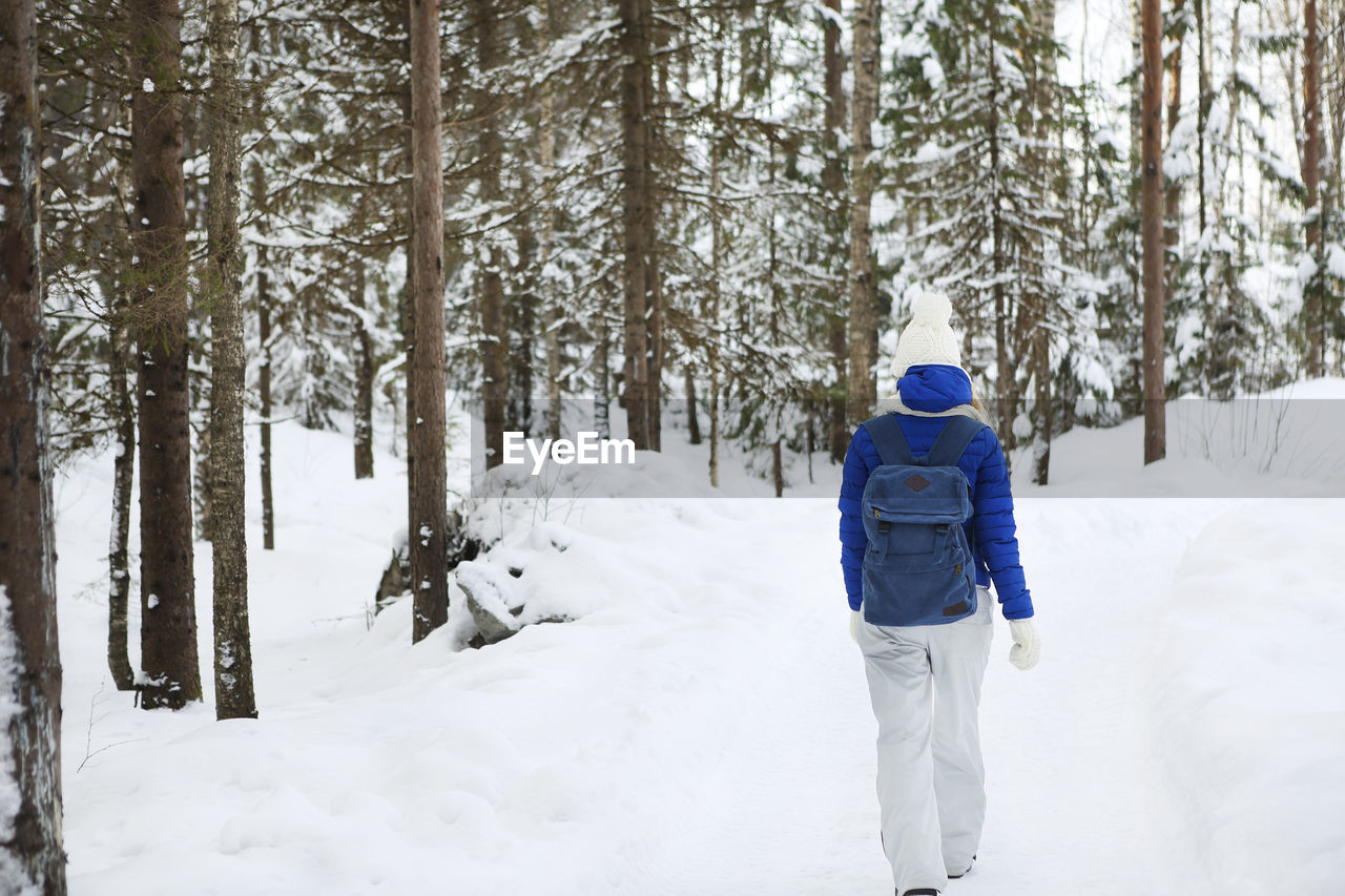 Rear view of man walking on snow covered land