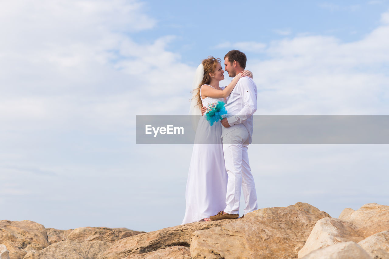 Woman standing on rock against sky