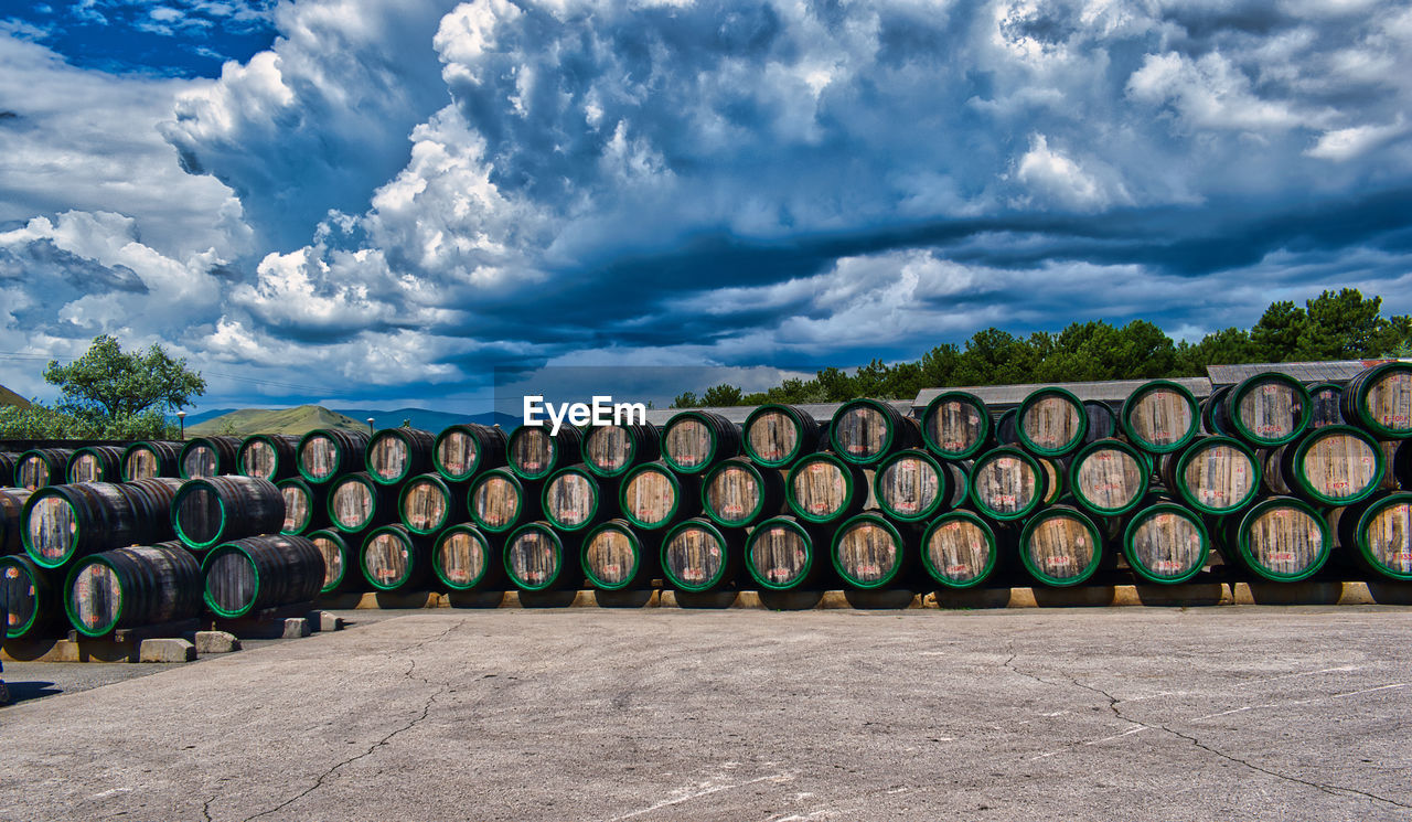 Stack of wine barrels on field against sky