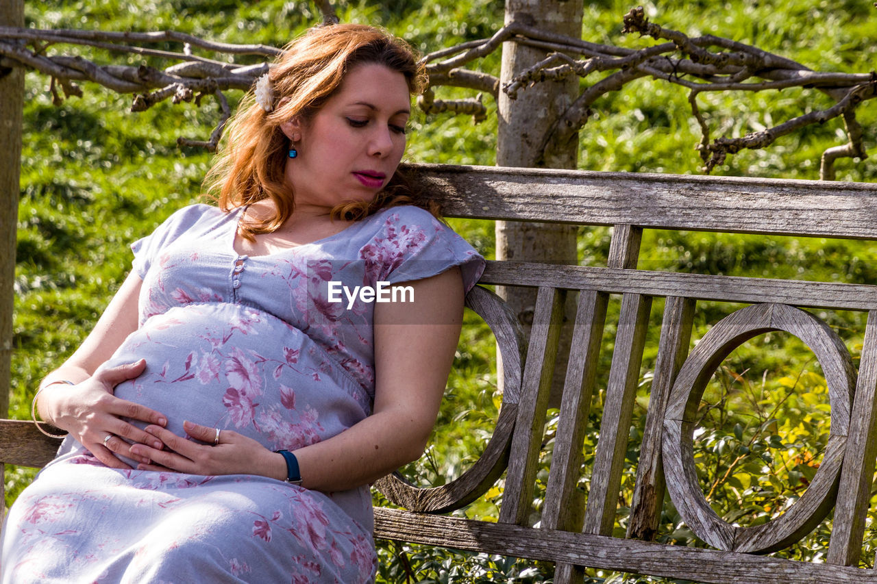 Pregnant woman sitting on bench at park