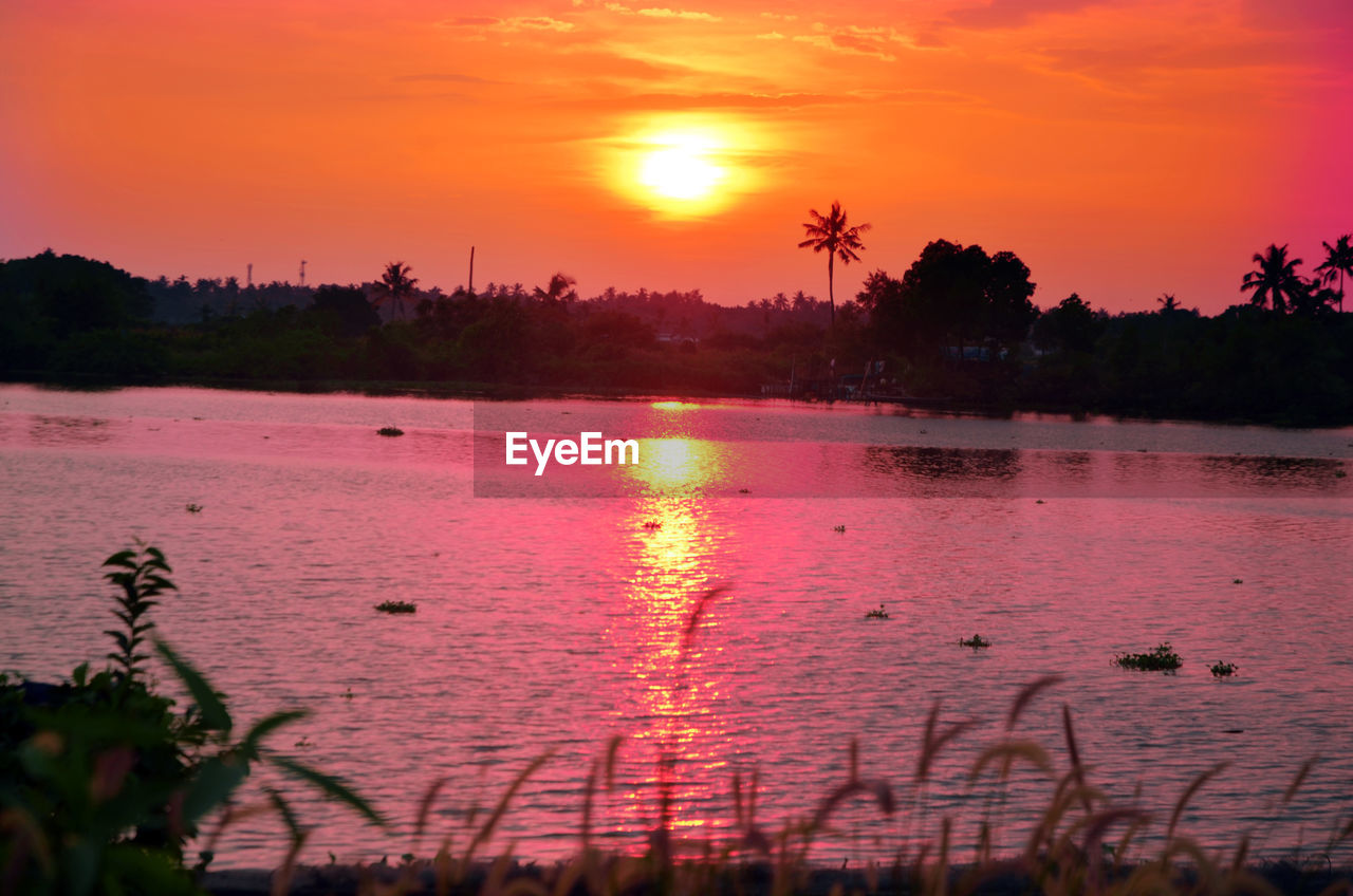 SCENIC VIEW OF LAKE AGAINST ORANGE SKY AT SUNSET