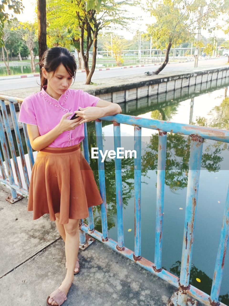 Woman using phone while standing by railing