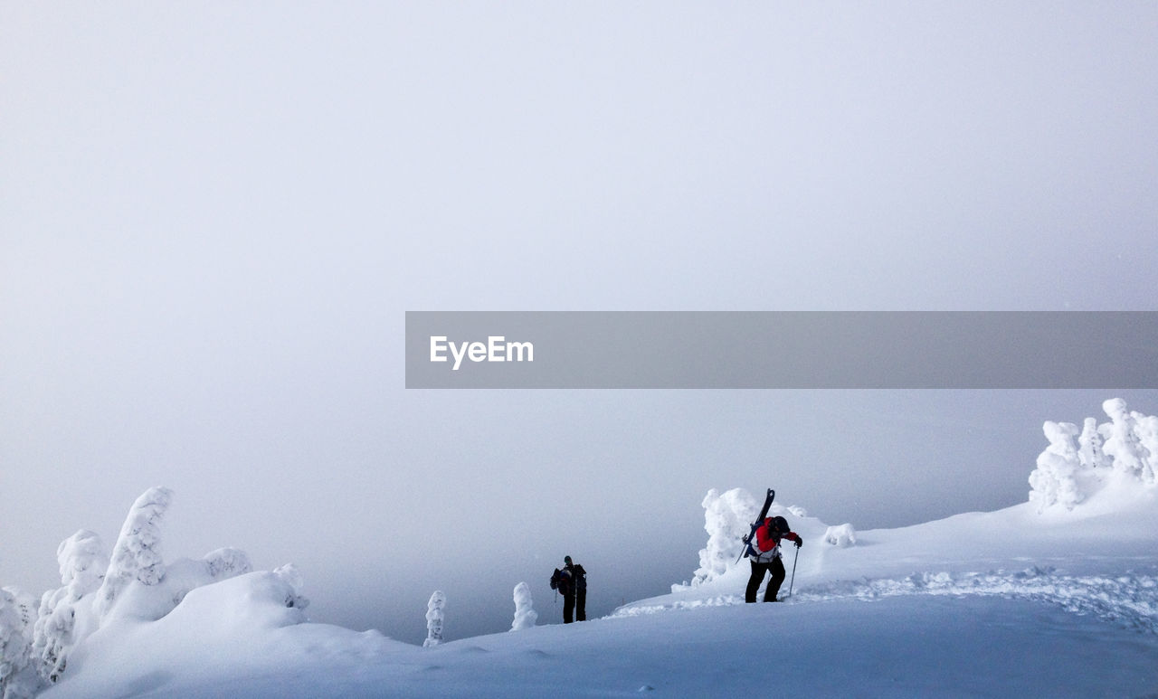 People skiing on snowcapped mountain against clear sky