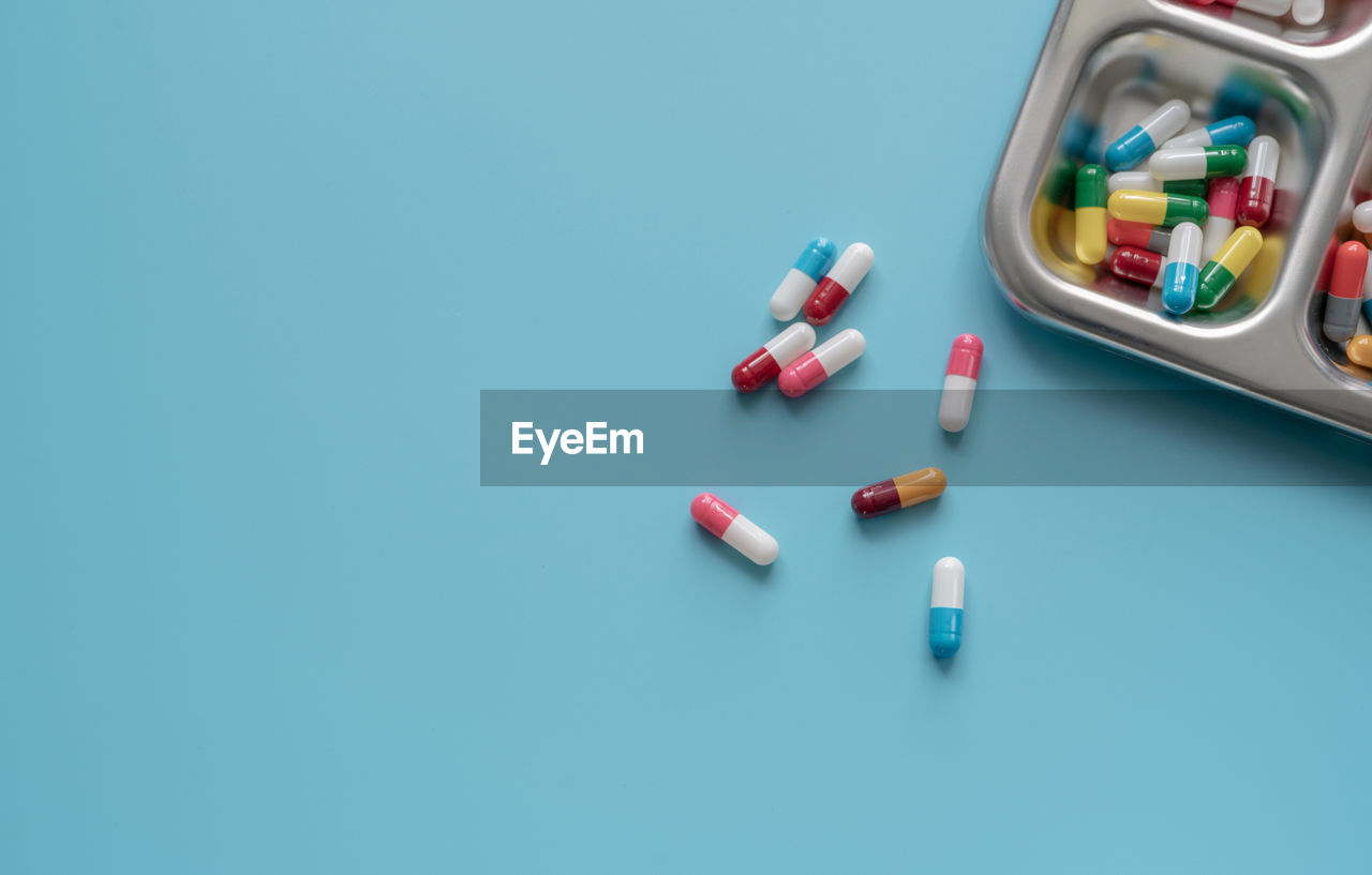 Above view of colorful antibiotic capsule pills on a tray and blue background. antibiotic drug 