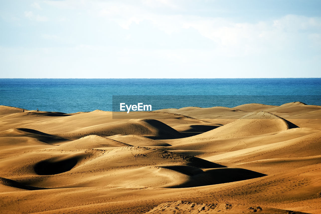 Scenic view of desert and sea against sky