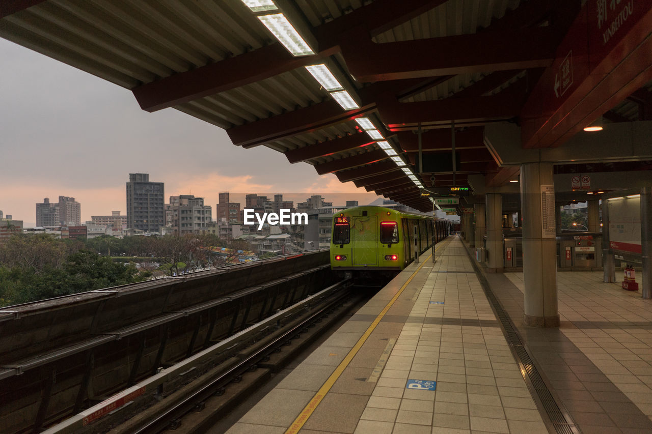 TRAIN AT RAILROAD STATION AGAINST SKY