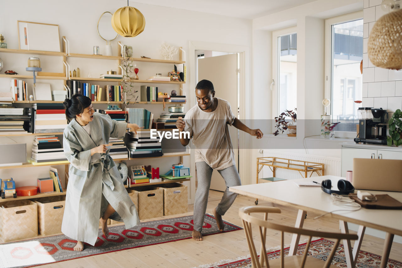 Cheerful couple dancing in living room at home